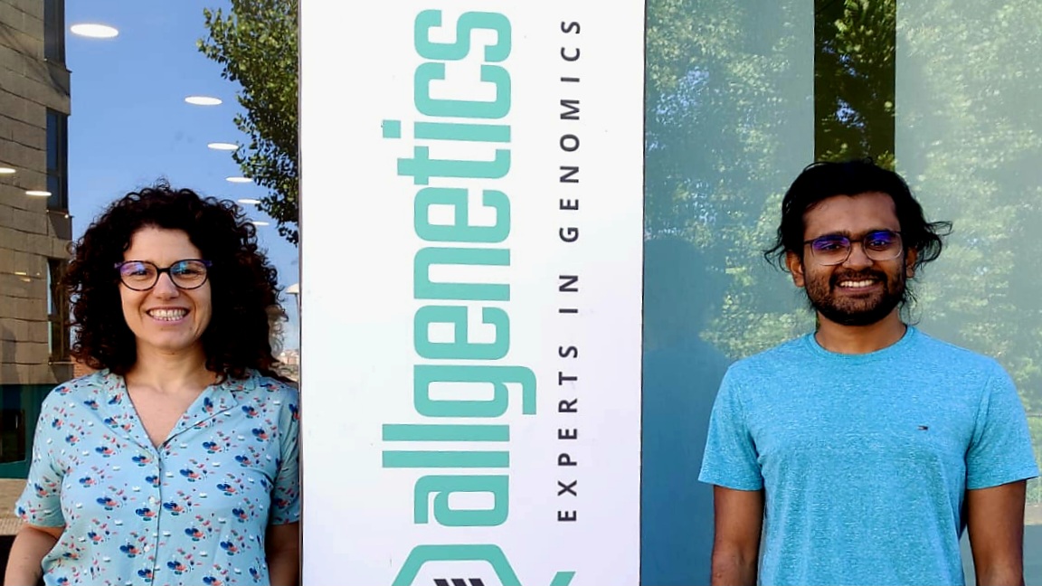 The image shows Dr Neus Marí-Mena and Yasas Wijesekara at the AllGenetics headquarters in Spain.