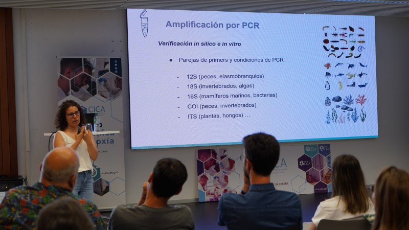 The photo shows Dr Neus Marí-Mena giving a talk about marine eDNA at UDC.