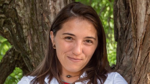 The image shows a portrait of Dr Chloe Fouilloux, winner of the AllGenetics-EMPSEB Award.